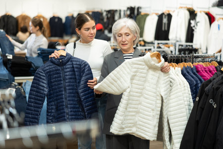 Old woman choosing white jacket in clothing storeの写真素材