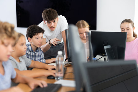 Positive man teacher together with the boy teaches how to work on computerの写真素材