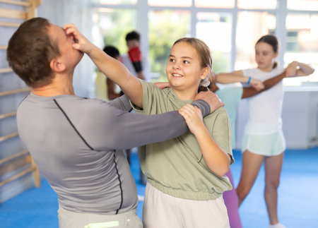 Teenage girl using painful technique to eyes in mock bout with instructor at self-defense classの写真素材