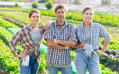 Man and two women pose in field among harvestの写真素材