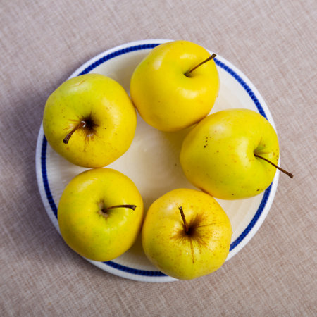 Ripe and juicy yellow golden delicious apples are laid out on plate.の写真素材