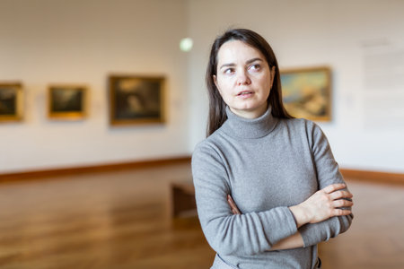 Female art lover viewing collection of paintings in art museumの写真素材