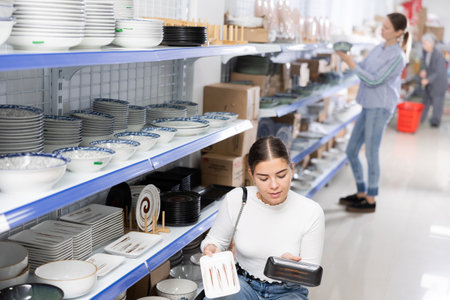 Young girl choosing square plates for serving sushi in Asian storeの写真素材