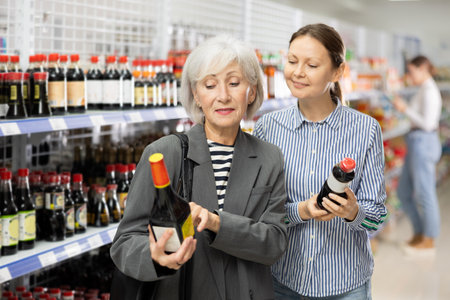 Female customer with senior mother is thinking about buying spicy and unusual soy sauce.の写真素材