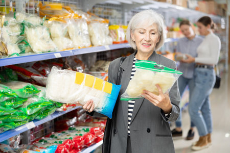 Elderly woman choosing noodles for dinner in Asian food storeの写真素材
