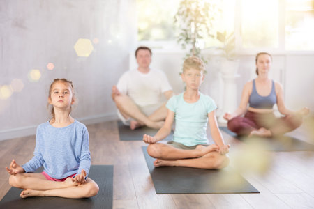 Teenage girl with her parents practices yoga in lotus positionの写真素材