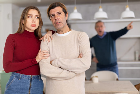 Elderly father scolds and shouts at a married couple. Quarrel in home kitchenの写真素材