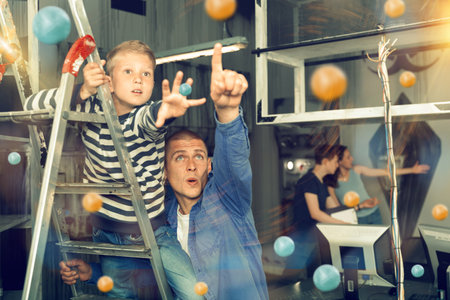 Father and son, looking for a way out of the escape room, saw the key to solving the puzzleの写真素材