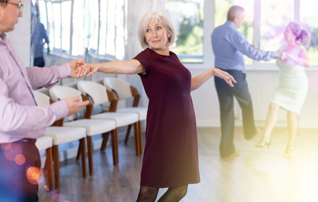 Smiling adult lady in elegant clothes learn to dance couples latin dance, energetic and fast jive in...