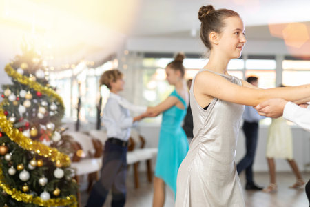Teenage girl dancing waltz with classmate during Christmas party at collegeの写真素材