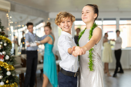 Teen boy and girl dancing waltz in couple during lesson at studio in New Year atmosphereの写真素材