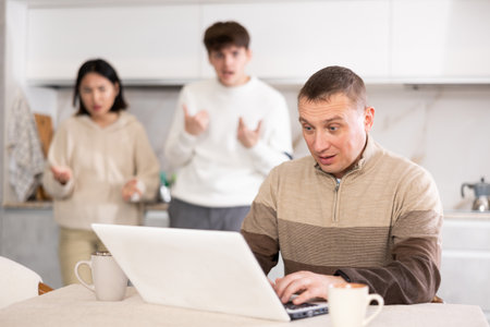 Dissatisfied son and daughter scold their father for playing computer gamesの写真素材