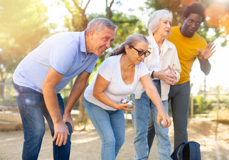 A group of multiracial mature adult people playing patanque game outdoors in a parkの写真素材