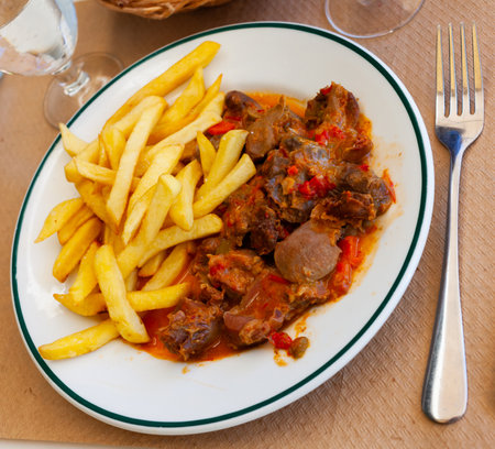 Chicken gizzards in vegetables salsa with fried potatoesの写真素材