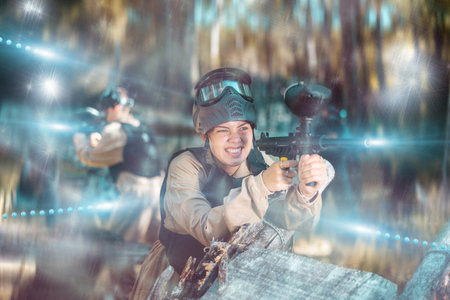 Woman fires a gun with passion while playing paintballの写真素材