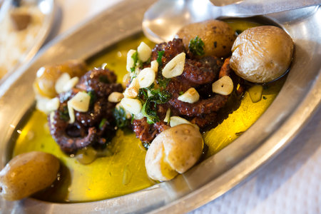 Roasted tasty octopus at plate with baked potatoes and garlicの写真素材