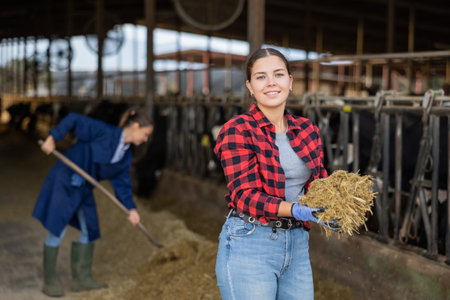 Farmer engaged in breeding of cows posing in cowshedの写真素材