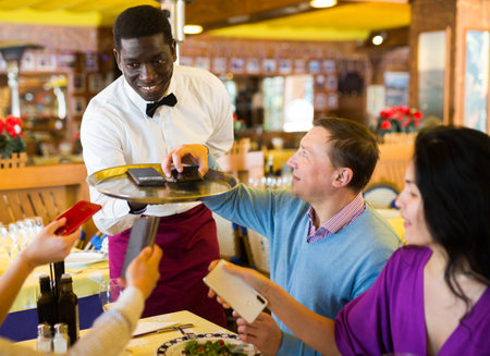People putting their phones on waiters tray in restaurantの写真素材