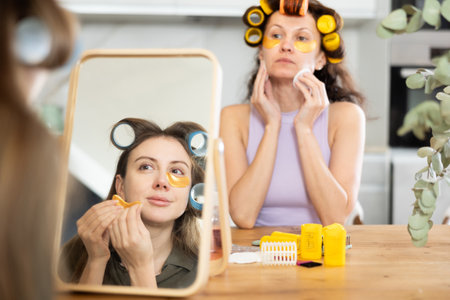 Women in colorful curlers applying eye patches and sharing beauty secretsの写真素材