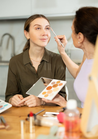 Makeup artist carefully shaping eyebrows to young womanの写真素材
