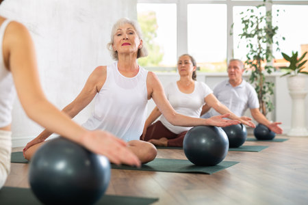 Group of elderly people doing pilates with soft ball in studioの写真素材