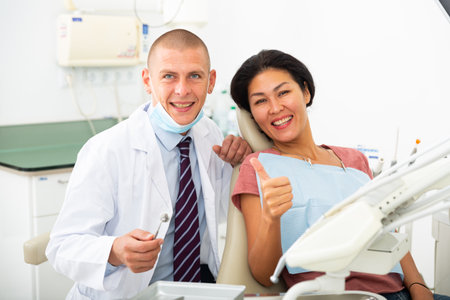 Portrait of a qualified smiling man dentist with a satisfied female patientの写真素材