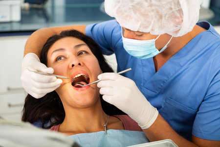 Dentist examining asian female patient teethの写真素材