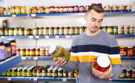 Adult man chooses pickled cucumbers and tomatoesの写真素材