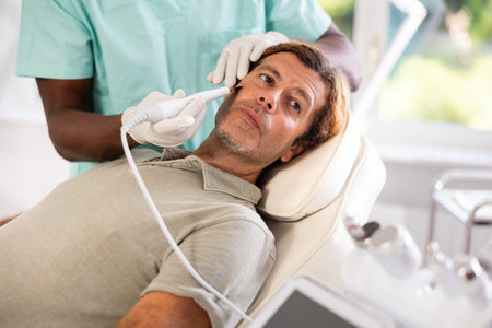 Adult man undergoing cosmetic facial treatment using ultrasonic shovelの写真素材
