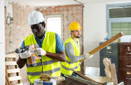 Two builders working on indoor construction siteの写真素材