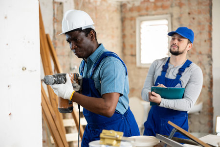 Foreman tells the builder where to drill holes with hammer drill