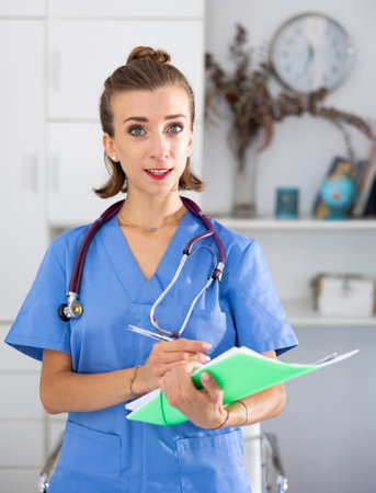 Smiling woman doctor holding paper folder and looking at cameraの写真素材