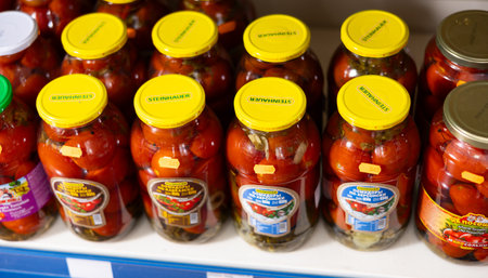 Russian goods store shelves have glass jar with canned pickled tomatoes and cucumbers.のeditorial素材