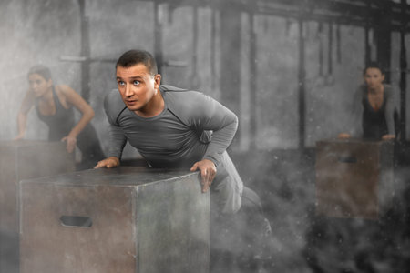 Focused man doing cross fit in gym. Active training