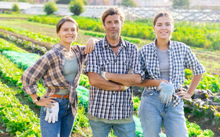 Portrait of three happy farmers against the backdrop of a field with vegetable harvestの写真素材
