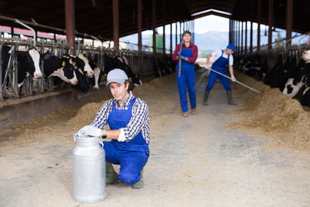 Adult male farmer with can works on dairy farmの写真素材