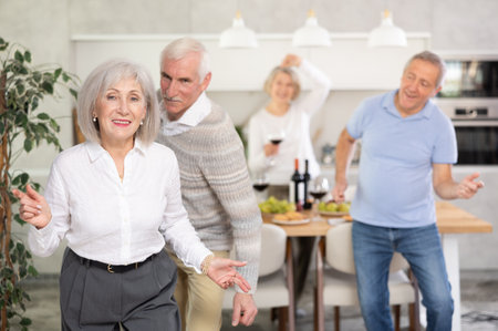 Senior men and women have fun dancing during house party.の写真素材