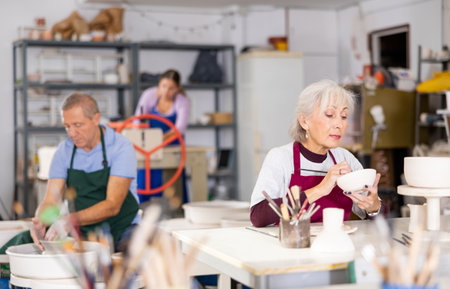 female potter paints finished vase in whiteの写真素材