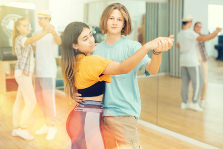 Group of young girls and boys dancing waltz indoors