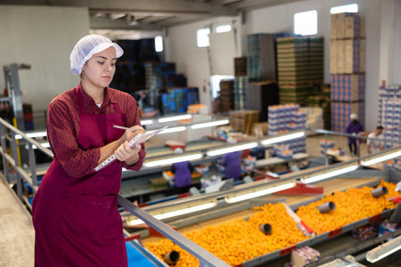 Positive female worker fills out a document at a citrus processing plant.