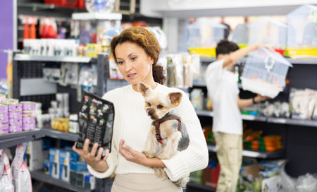 Woman with Yorkshire terrier choosing dry dog food in pet store