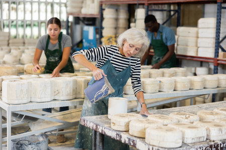 Elderly woman potter filling mould with melted clayの写真素材