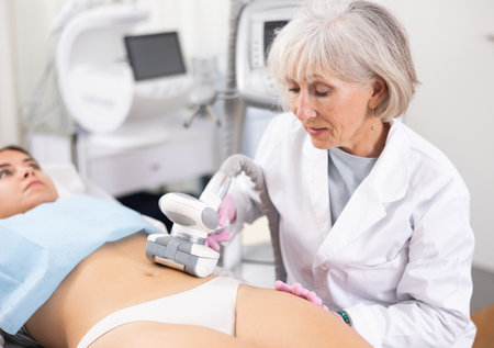 Old woman specialist doing LPG massage of belly of young womanの写真素材