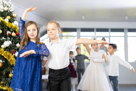 Little children practicing waltz dance in school-hall decorated with Christmas-treeの写真素材