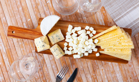 Snack prepared on serving board - assorted oh sliced, large pieces of blue cheese, and cheese ballsの写真素材