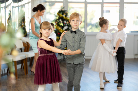 Little children in festive clothes dance foxtrot dance while celebrating Christmasの写真素材