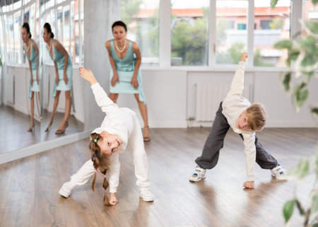Tween girl and boy rehearsing popping techniques in street dance studioの写真素材