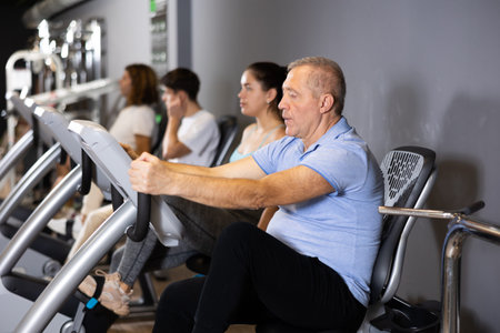 Elderly man doing cardio training on stationary bike in gym