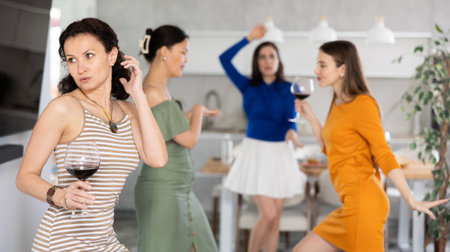 Carefree woman dancing with female friends at home partyの写真素材