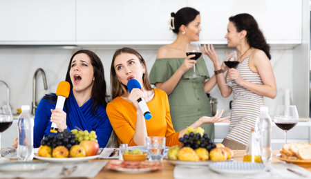 Happy smiling women celebrating friendship, birthday or festive season singing at home